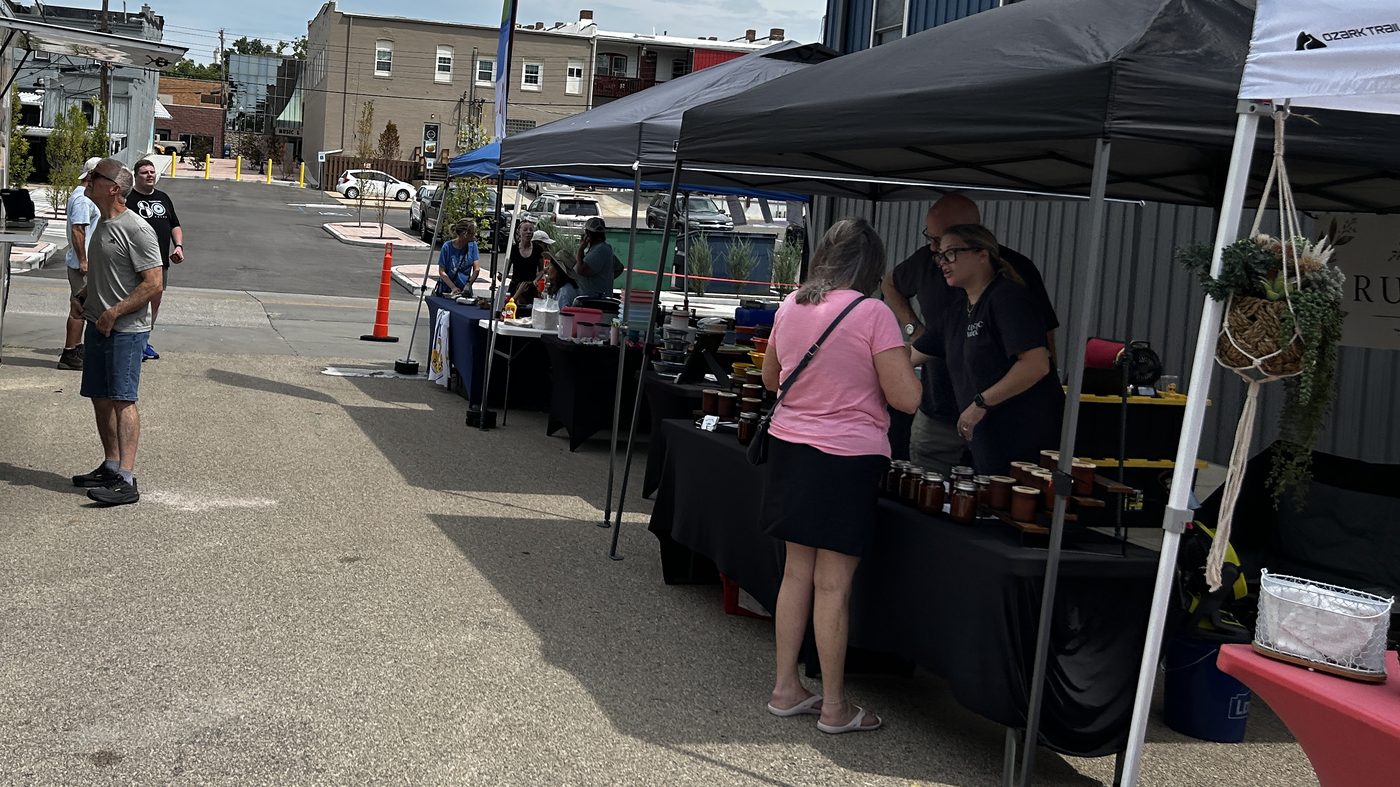 A shopper at a jam and salsa stall behind Festus Main Street, with a coffee truck across the aisle