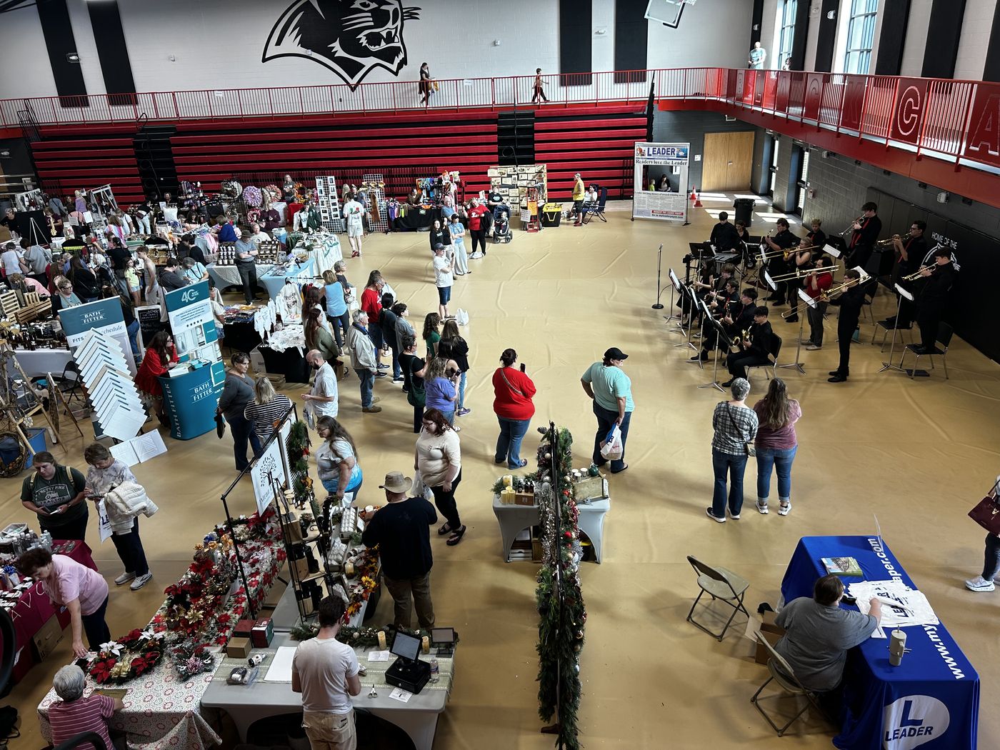 Vendor booths and shoppers filling the Herculaneum High School gym floor, seen from the upper level