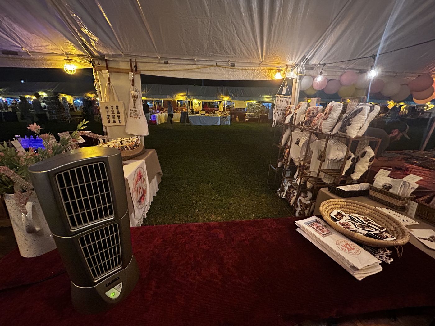Looking down the aisle of the big vendor tent at Pevely Days, booths on both sides under string lights